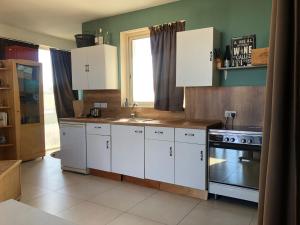 uma cozinha com armários brancos, um lavatório e um fogão em Penthouse in Kappara em San Ġwann