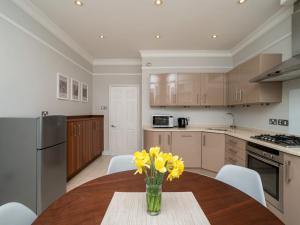 a kitchen with a table with yellow flowers in a vase at Pass the Keys Spacious 3 bed apartment in prime central location in Bath
