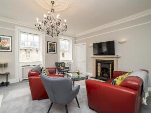 a living room with red furniture and a chandelier at Pass the Keys Spacious 3 bed apartment in prime central location in Bath