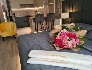 Una cama con un ramo de rosas rosas. en Wellness Apartments, en Varaždin