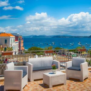 a patio with chairs and tables and a view of the water at Hotel Noris in Ischia