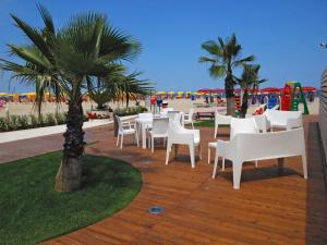 a patio with white tables and chairs and a beach at HOTEL BALTIC in Alba Adriatica