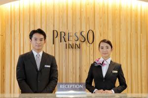 two people in suits standing in front of a wall at Keio Presso Inn Shinjuku in Tokyo
