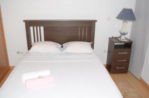 1 dormitorio con 1 cama y mesita de noche con lámpara en Apartamento Terra Branca, en Praia