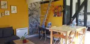 een eetkamer met een tafel en een gele muur bij La petite maison in Le Bosc-Roger-en-Roumois