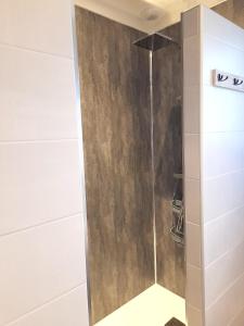 a shower in a bathroom with a wooden wall at Maison confortable à Coltines 80 m² avec jardin spacieux in Coltines +18 photos