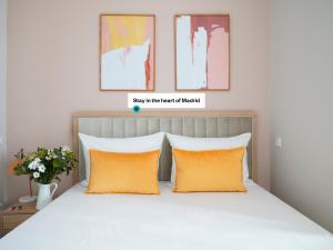 ein Schlafzimmer mit einem Bett mit zwei orangefarbenen Kissen in der Unterkunft numa I Script in Madrid