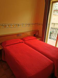 2 czerwone łóżka w sypialni z oknem w obiekcie Hotel San Pietro w mieście Letojanni
