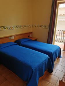 two blue beds in a room with a window at Hotel San Pietro in Letojanni