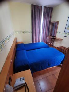 a bedroom with a blue bed and a desk at Hotel San Pietro in Letojanni