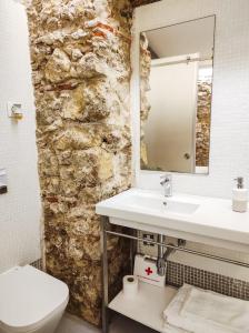 een badkamer met een wastafel en een stenen muur bij Casa da Sé Cathedral Suites in Coimbra