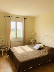 a bedroom with a large bed and a window at Le Claux du Puits by Ateya Vacances in Saint-Trinit