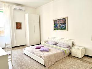 Dormitorio blanco con cama con almohadas moradas en Camera Matrimoniale privata in appartamento condivisibile, en Salerno