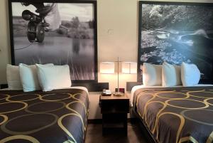 a hotel room with two beds and a picture on the wall at Super 8 by Wyndham Greeley in Greeley