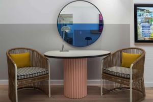 einem runden Tisch mit 2 Stühlen und einem Spiegel in der Unterkunft QT Gold Coast in Gold Coast