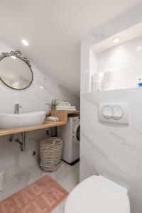 een witte badkamer met een wastafel en een spiegel bij Bella Ciao Apartments in Rijeka