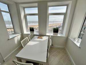 a white table and chairs in a room with windows at Apartments @52 in Bridlington
