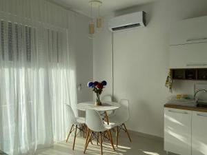 a table and chairs in a kitchen with a vase of flowers at Valamar ED Apartment in Hamallë
