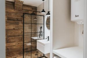La salle de bains est pourvue d'un mur en bois, d'un lavabo et d'un miroir. dans l'établissement Contemporary Industrial Apartment by REMS, à Malaga