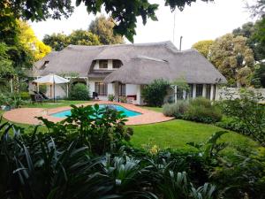 a house with a thatched roof and a swimming pool at Libra Lodge in Sandton