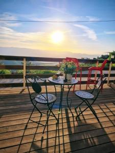 a table and two chairs on a deck with the sunset at Sunset B&B in Ein Kinya
