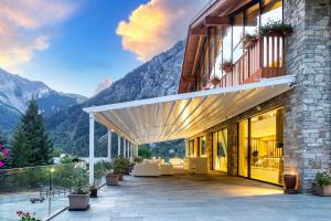 a building with a patio with mountains in the background at Grand Hotel Courmayeur Mont Blanc, by R Collection Hotels in Courmayeur