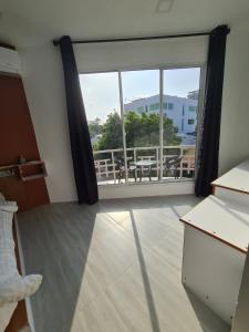 um quarto com uma grande janela com uma mesa e uma varanda em Merijaan Maldives em Maafushi