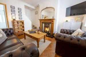 sala de estar con muebles de cuero y chimenea en Gilly Cottage en South Cave