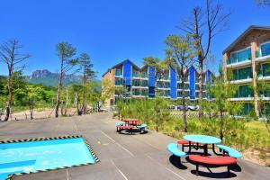 a pool with picnic tables in front of a building at Ulsanbawi Rock View Apartment in Sokcho