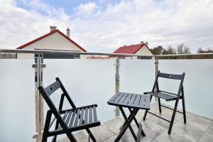 dwa krzesła i stół na balkonie w obiekcie Południowa Przystań Dębki by Renters w Dębkach