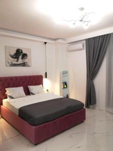 ein Schlafzimmer mit einem großen Bett mit rotem Kopfteil in der Unterkunft Promenada Beach Residence in Mamaia Nord – Năvodari