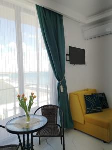 ein Wohnzimmer mit einem Tisch und einer gelben Couch in der Unterkunft Promenada Beach Residence in Mamaia Nord – Năvodari