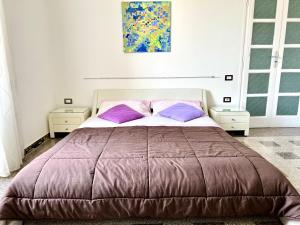 1 dormitorio con 1 cama grande con almohadas moradas en Camera matrimoniale privata in appartamento condivisibile en Salerno