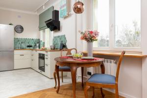a kitchen with a table and chairs and a refrigerator at Apartment Warsaw Wiktorska by Renters in Warsaw