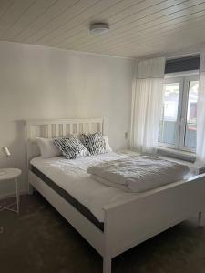 a white bedroom with a bed and a window at Haus am Grimnitzsee mit Garten in Joachimsthal