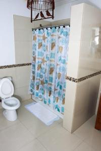 a bathroom with a shower curtain with a toilet at Redknot Manor Guest house/Hotel in Matthew Town
