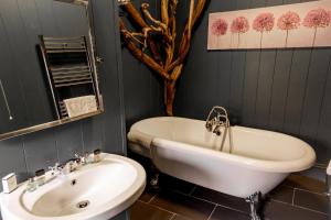 
a bathroom with a tub, sink and mirror at No1 Hotel in Wooler
