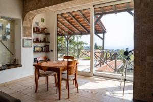 a dining room with a table and a large window at Villa immersa nel verde dell Etna in Piedimonte Etneo