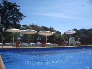 una piscina con sombrillas, mesas y sillas en Studios Coll, Terrace & Pool, en Sant Martí d’Empúries