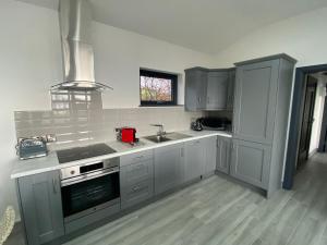 uma cozinha com armários brancos, um lavatório e um fogão em Tullybay Holiday Lodges em Enniskillen