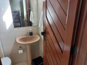 a bathroom with a sink and a wooden door at Pousada Hotel Santa Helena in Juazeiro do Norte