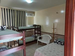 a dorm room with two bunk beds and a chair at Pousada Hotel Santa Helena in Juazeiro do Norte