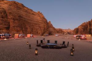 a table and chairs in the middle of a desert at Caravan by Habitas AlUla in Al Ula