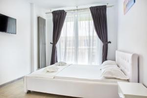 a white bed in a room with a window at Apartament Iris by Alz in Năvodari