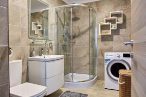 a bathroom with a shower and a toilet and a washing machine at Apartament Iris by Alz in Năvodari