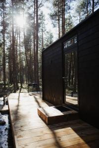 uma casa com um deque de madeira na floresta em ÖÖD Hötels Laheranna SÄRA -with sauna em Punakivi