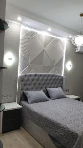 Schlafzimmer mit einem großen Bett mit einem gepolsterten Kopfteil in der Unterkunft Charming and modern apartment at heart of Tashkent in Taschkent
