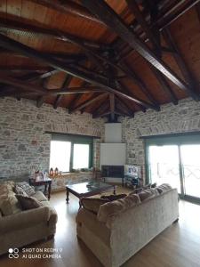 una sala de estar con 2 sofás y una pared de ladrillo en Villa Sklithro in the heart of the forest with magnificent view of the sea just 10 minutes from it, en AgiaKampos