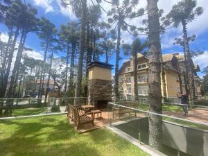 a building with a park with benches and trees at Excelente apartamento em Gramado/RS no Condomínio Casa de Pedra in Gramado