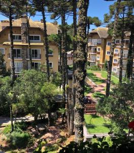 un immeuble avec un banc devant des arbres dans l'établissement Excelente apartamento em Gramado/RS no Condomínio Casa de Pedra, à Gramado